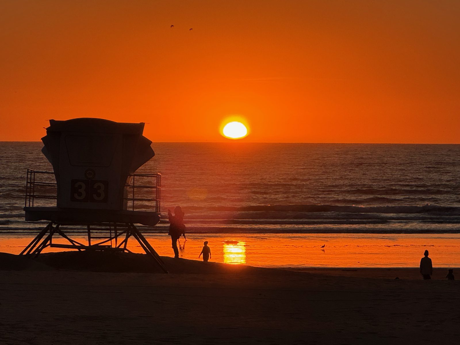 A parent and child on the beach at sunset